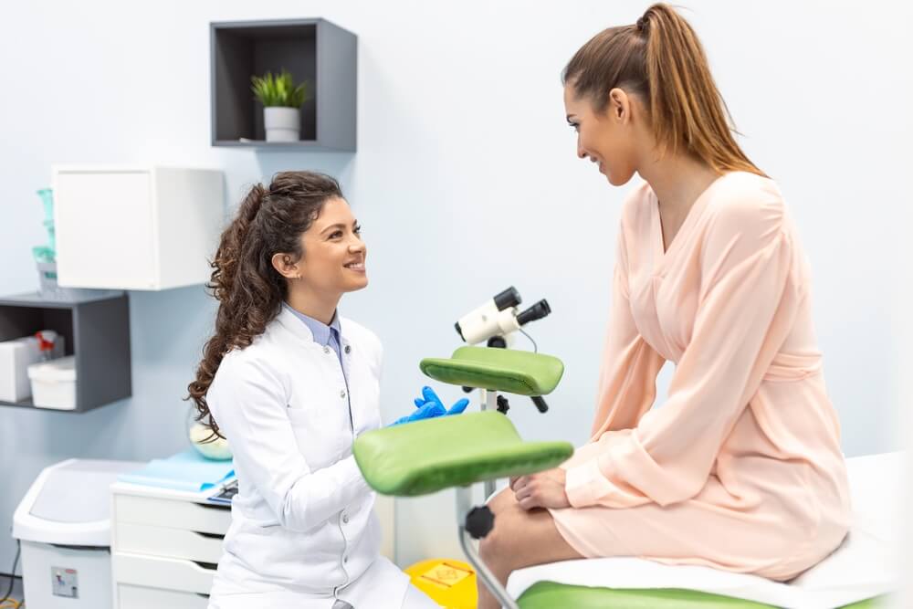 Gynecologist Preparing for an Examination Procedure for a Pregnant Woman Sitting on a Gynecological Chair in the Office