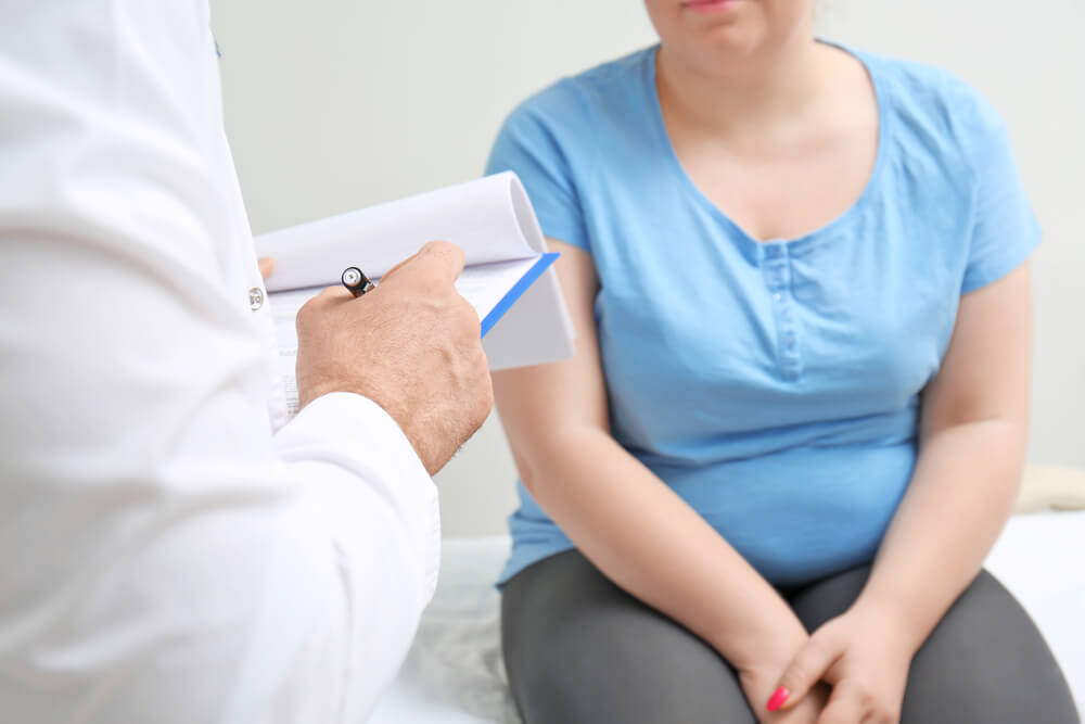 Overweight Woman Discussing Test Results With Doctor in Hospital