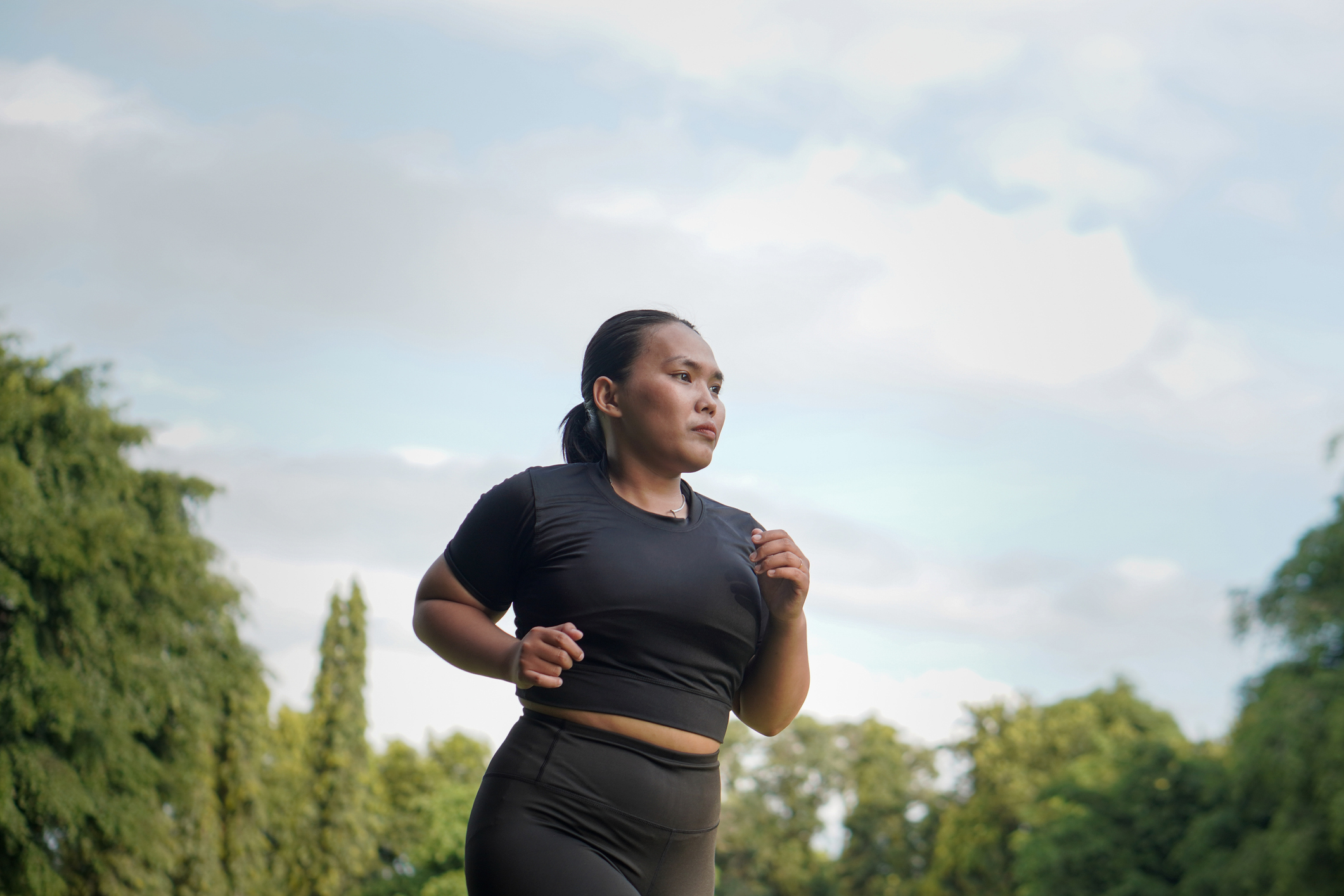 Confident Asian woman wearing sportswear jogging and running at outdoor public park
