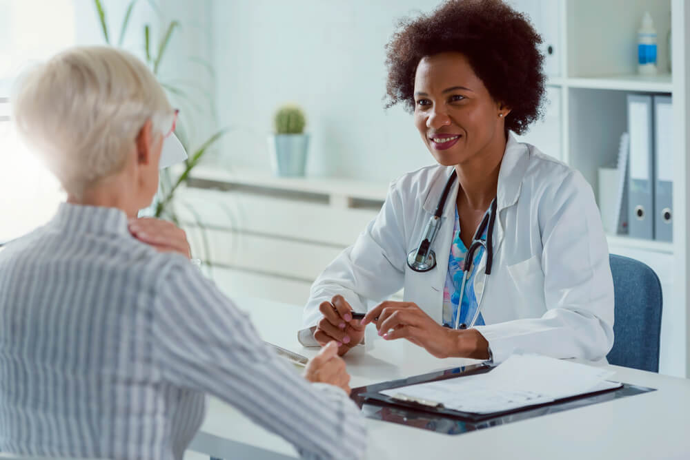 A Female Doctor Sits at Her Office and Examining Elderly Female Patient