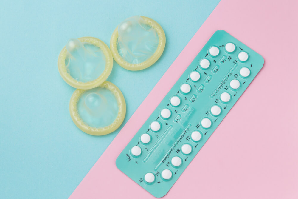 Contraceptive Pills and Condoms on Colored Background. 