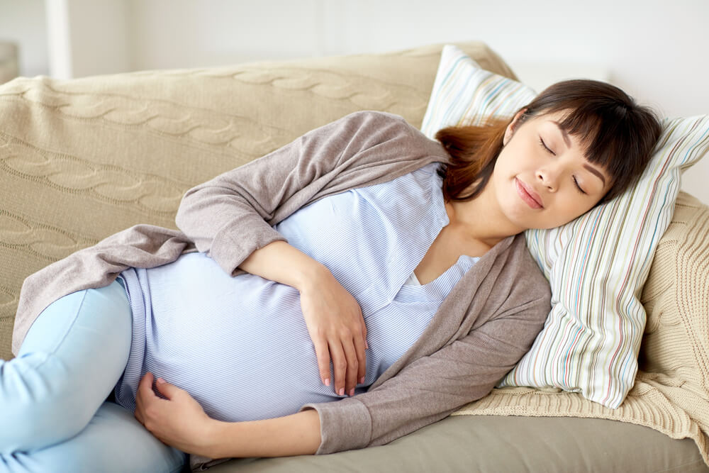 Pregnancy, Rest, People and Expectation Concept - Happy Pregnant Woman Sleeping on Sofa at Home