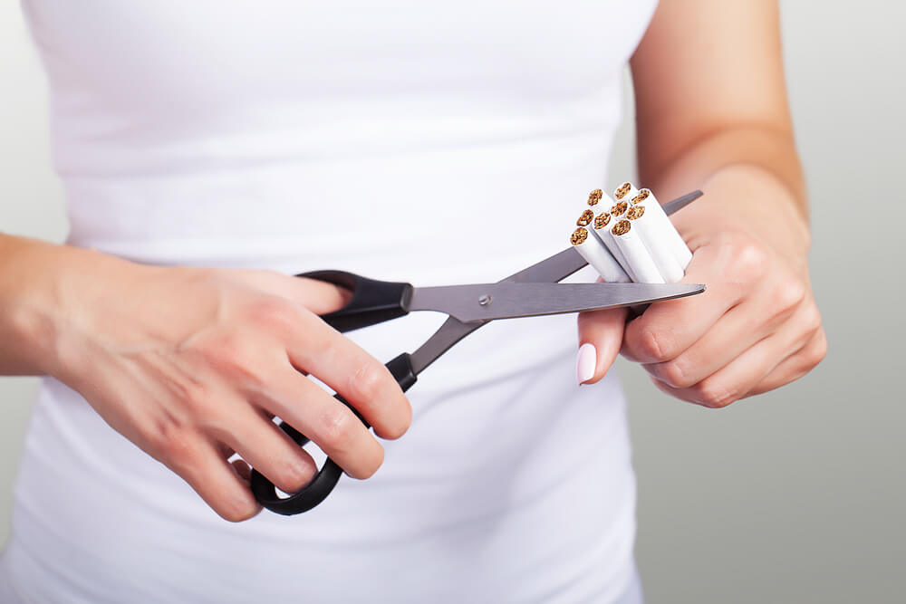 Young Woman Cutting Cigarettes With Scissors.