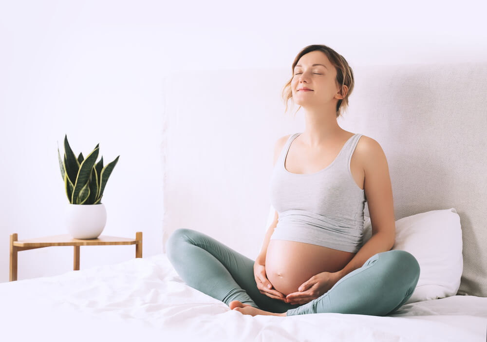 Pregnant Woman in Lotus Pose Doing Meditation or Breathing Exercises for Healthy Pregnancy and Preparing Body for Childbirth. 