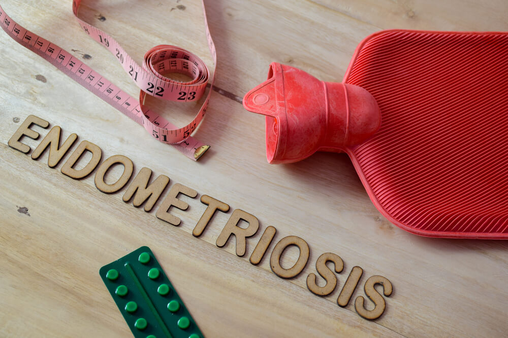 Endometriosis (A Painful Disorder) Written in 3D Wooden Alphabet Letters on Wood Surface With Medication, Tape Measure for Weight Gain and Hot Water Bag for Menstrual Pain