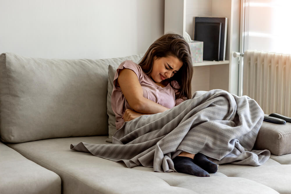 Unhappy Woman Holding Hands on Stomach Suffering From Abdominal Pain With Eyes Closed