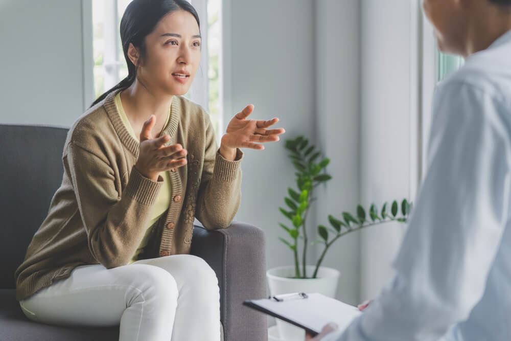 Stressed Asian Patient Talking With Personal Psychologist in Therapist Session Have a Burnout in Work at Clinic in Office Room.