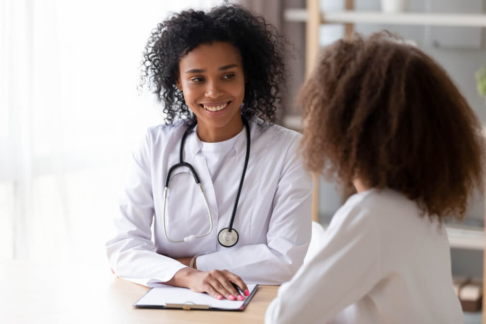American Doctor Psychotherapist, Therapist Counsellor or Pediatrist in White Coat Listens Teen Girl During Reception at Clinic