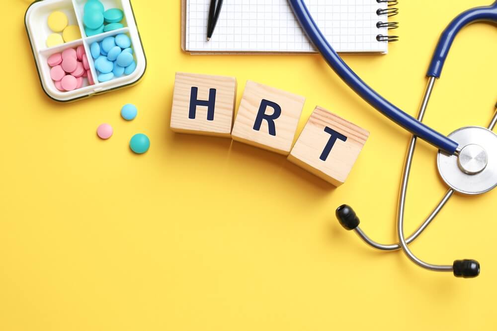 Wooden Cubes With Abbreviation Hrt, Pills, Stethoscope and Notebook on Yellow Background, Flat Lay