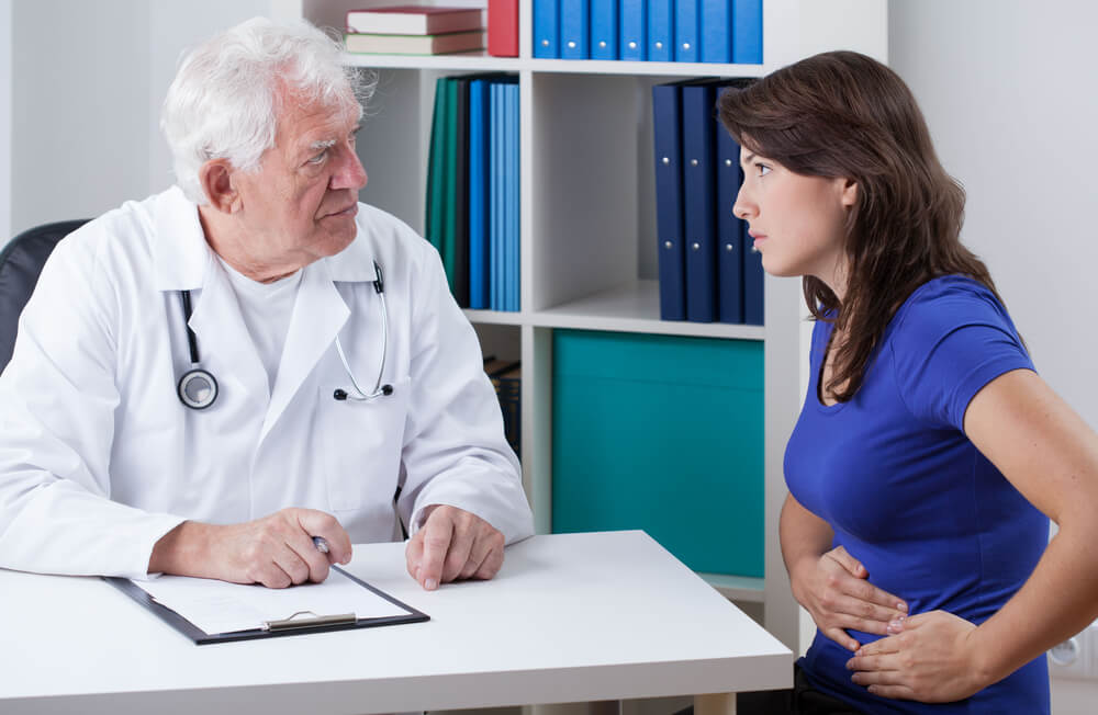 Young Woman With Stomach Pain Visiting Senior Doctor