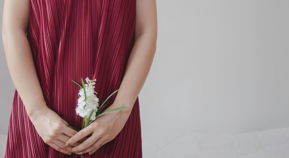 A Girl Wearing Red Dress Holding White Flower Close to Her Intimate Area