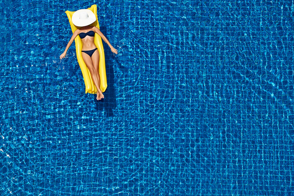 Top View of Slim Young Woman in Bikini on the Yellow Air Mattress in the Big Swimming Pool.