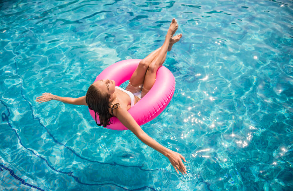 Young Beautiful Woman Is Relaxing in Swimming Pool With Rubber Ring.