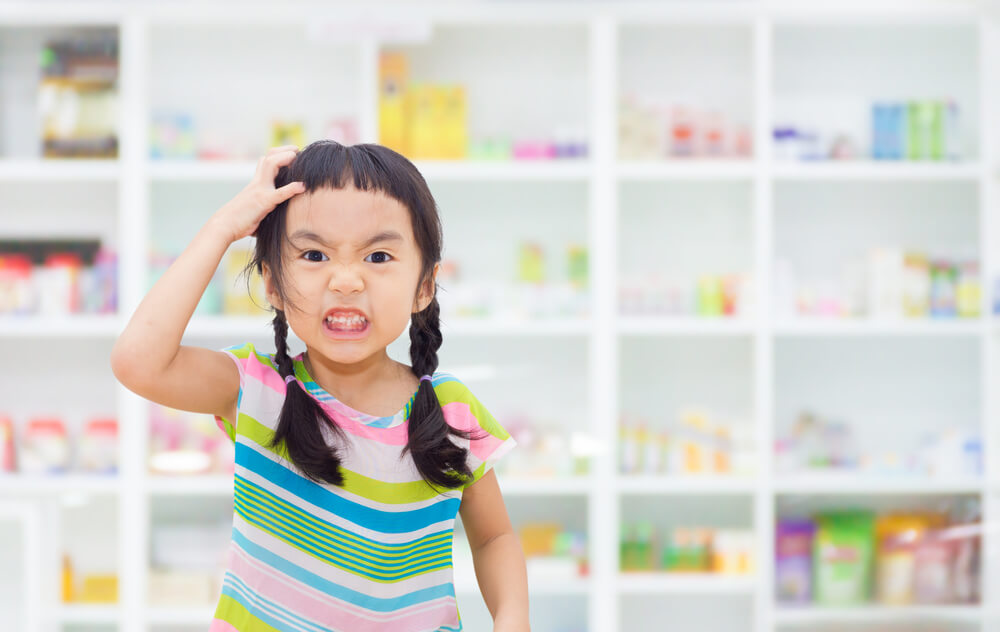 Asian Kid Is Stressed Drug Shelf in the Pharmacy Is the Background