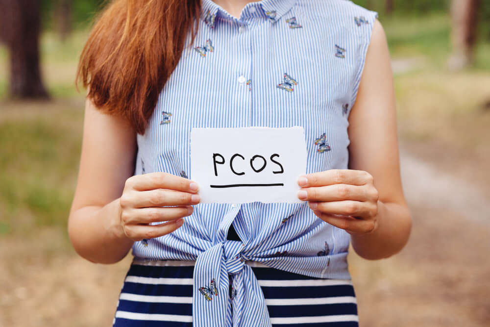 PCOS - Polycystic ovary syndrome, woman hormone sickness lettering on paper in womans hands