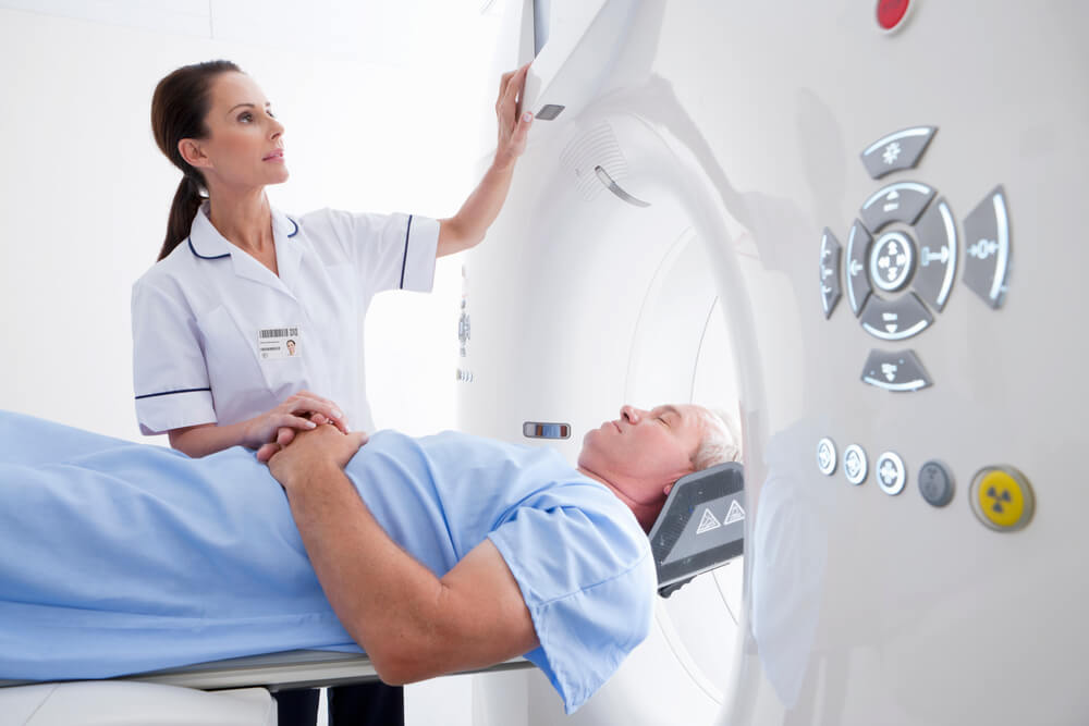 Close Up of a Nurse Operating a CT Scan Machine While a Patient Is Laying On It