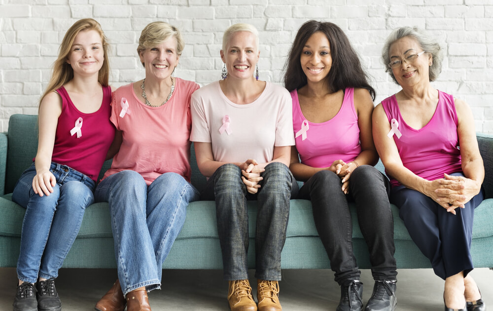 Women at Different Age Sitting on Sofa With Pink Ribbon on Their T-Shirts