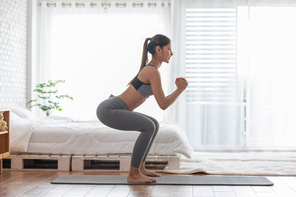 Woman in Sportswear Workout Squat Excercise at Home in Bedroom
