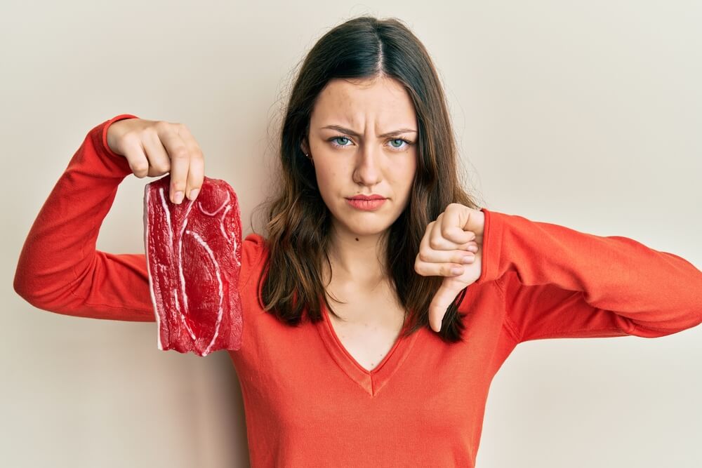 Young Brunette Woman Holding Raw Beef Steak With Angry Face