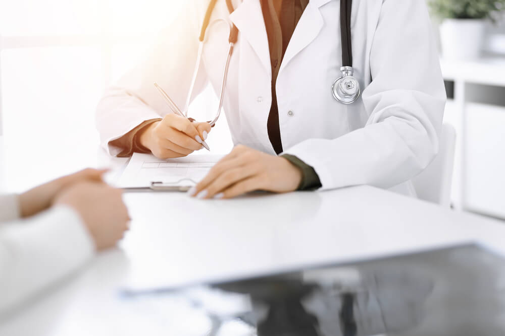 Unknown Woman-doctor and Female Patient Sitting and Talking at Medical Examination in Sunny Clinic, Close-up.