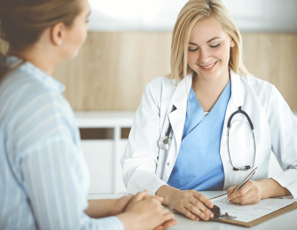 Woman-doctor and Patient Sitting and Talking in Hospital or Clinic.