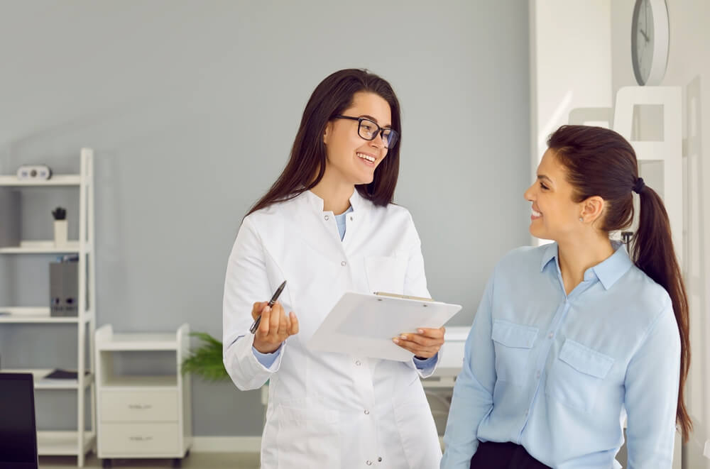 Friendly Cheerful Nurse or Doctor at Modern Clinic Talking To Patient.