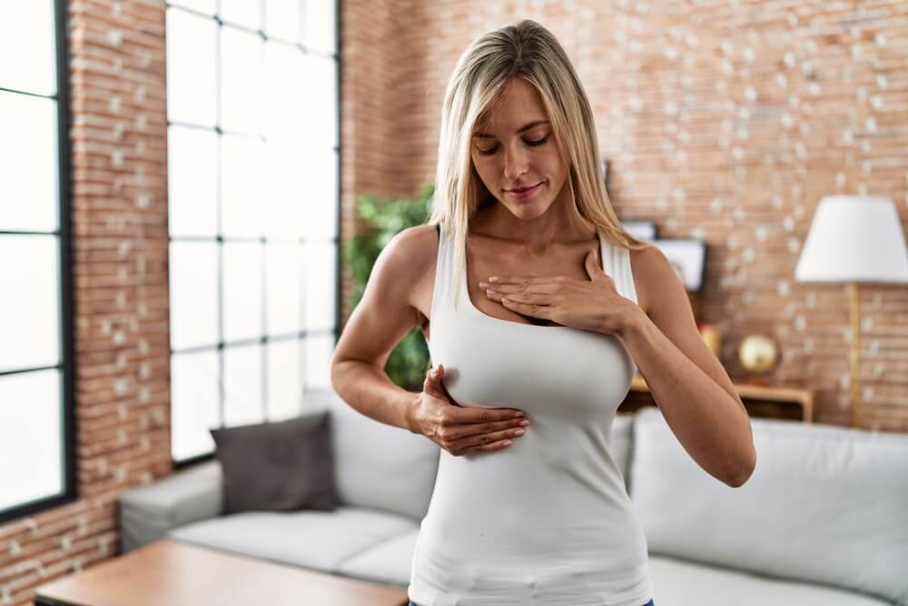 Young Blonde Woman Worried Examining Breast At Home