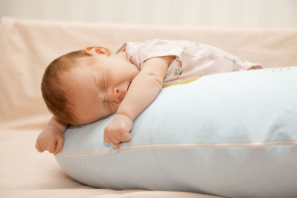 Newborn Baby Laying On The Pillow On His Tummy And Yawning