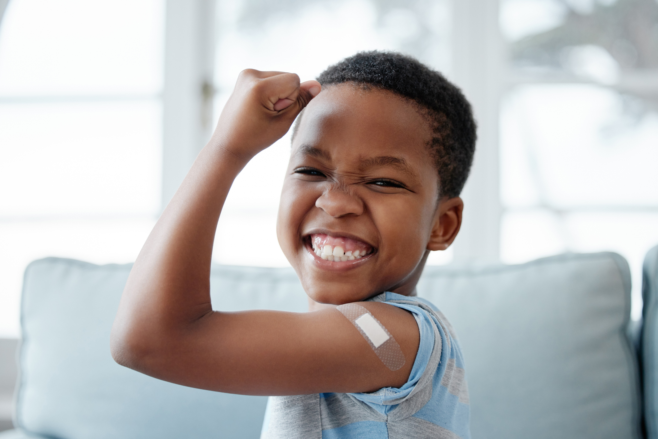 A child with a band aid on their arm representing vaccination for children.
