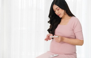 top_blog_diabetes-management-in-pregnancy_300x192 young pregnant woman holding glucose meter and checking blood sugar level by herself at home. gestational diabetes concept.