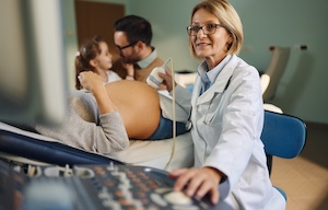 top_blog_obstetric-diagnostic-ultrasound_300x192 Happy gynecologist doing an ultrasound on pregnant woman who came with her family to the appointment.