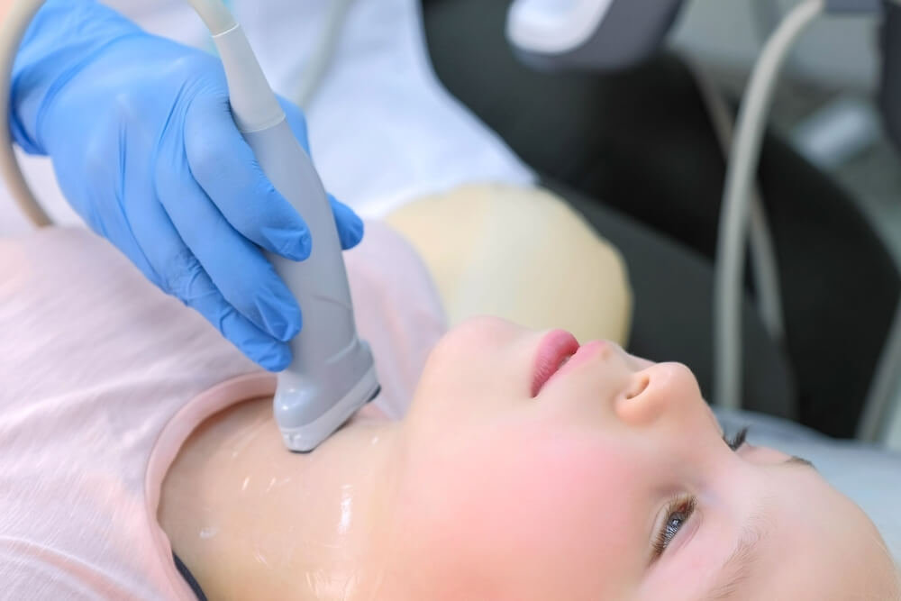 Doctor examining patient child girl thyroid gland using ultrasound scanner machine