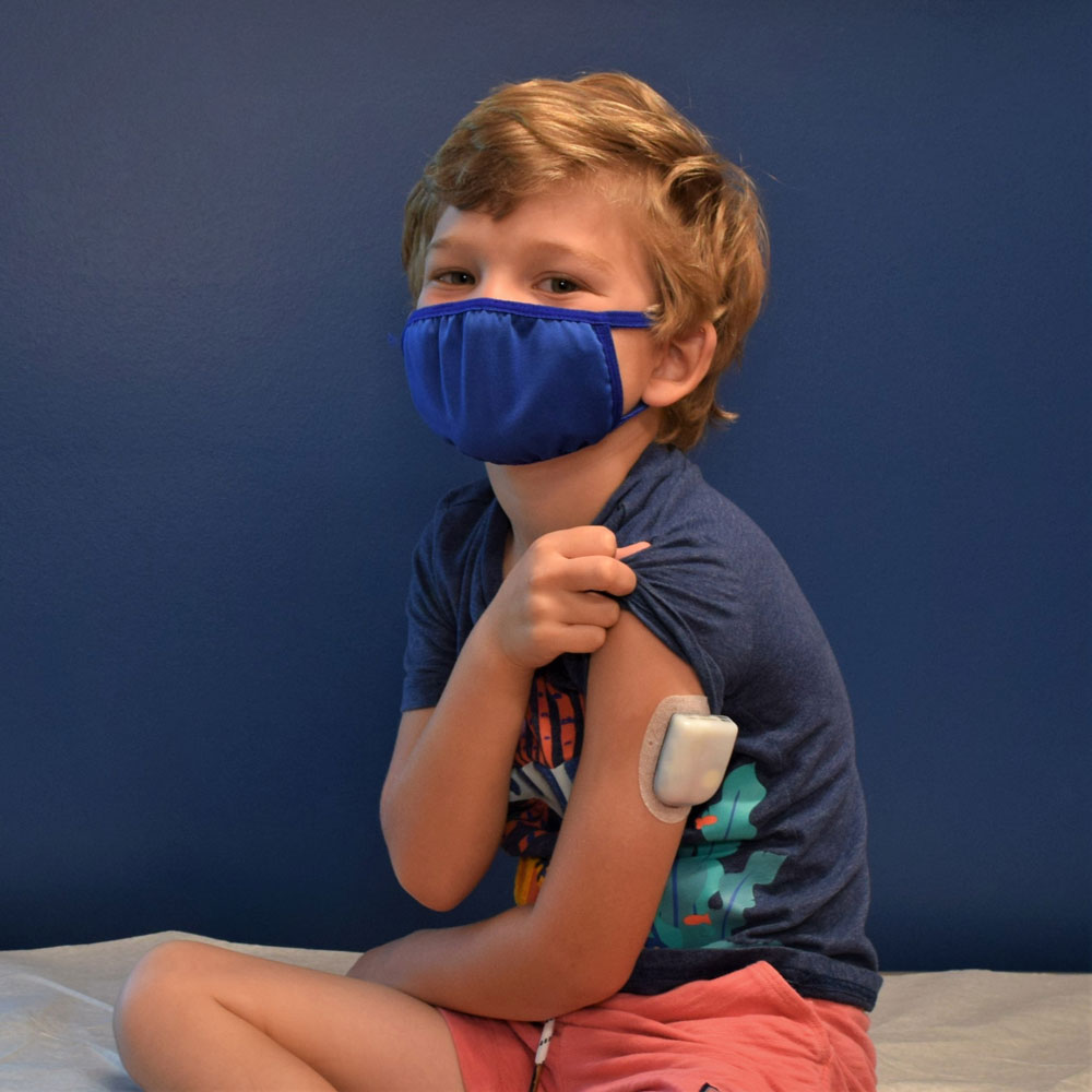 Young Boy With a Face Mask Showing His Insulin Patch