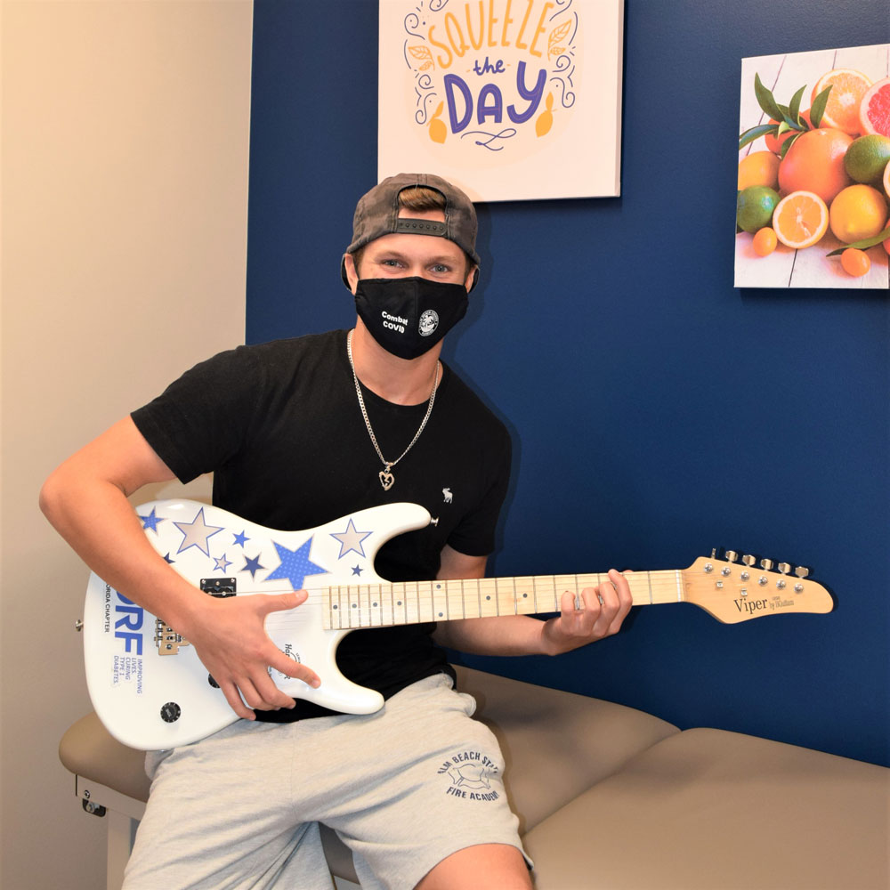 Teen Boy Playing a Guitar While Wearing a Face Mask