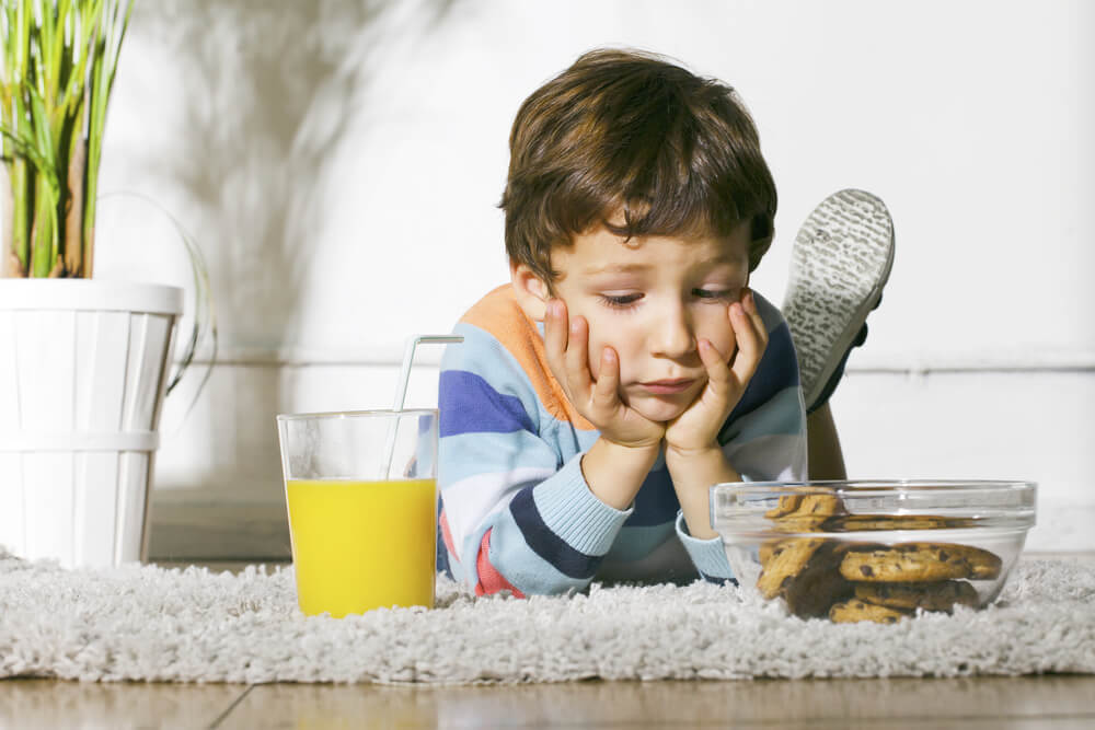 Little Boy With Cookies and Orange Juice Stretching on Carpet