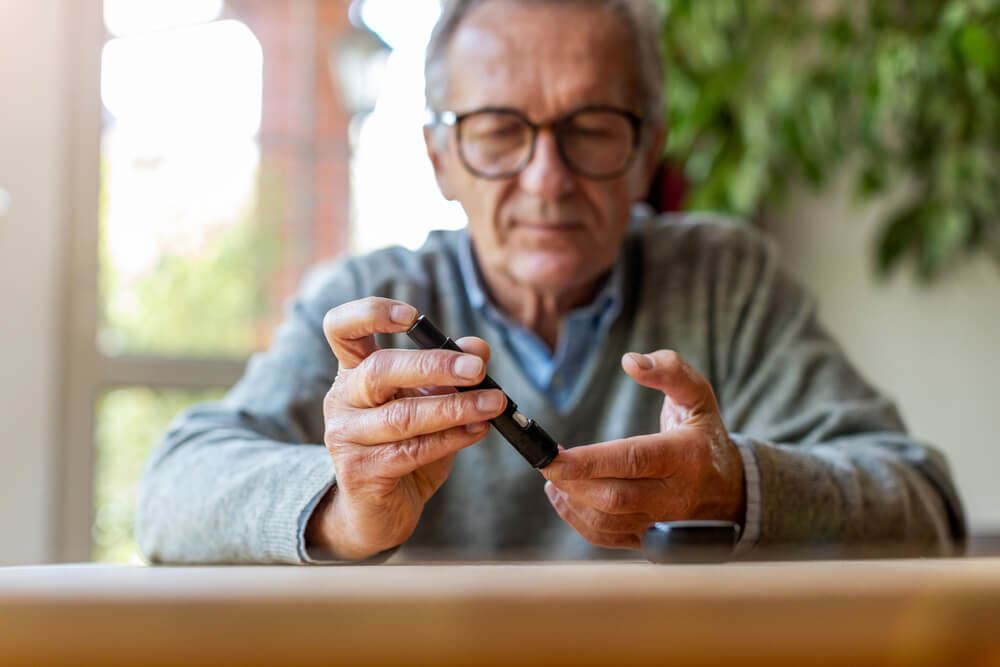 Mature Man Checking Blood Sugar Level With Glucometer