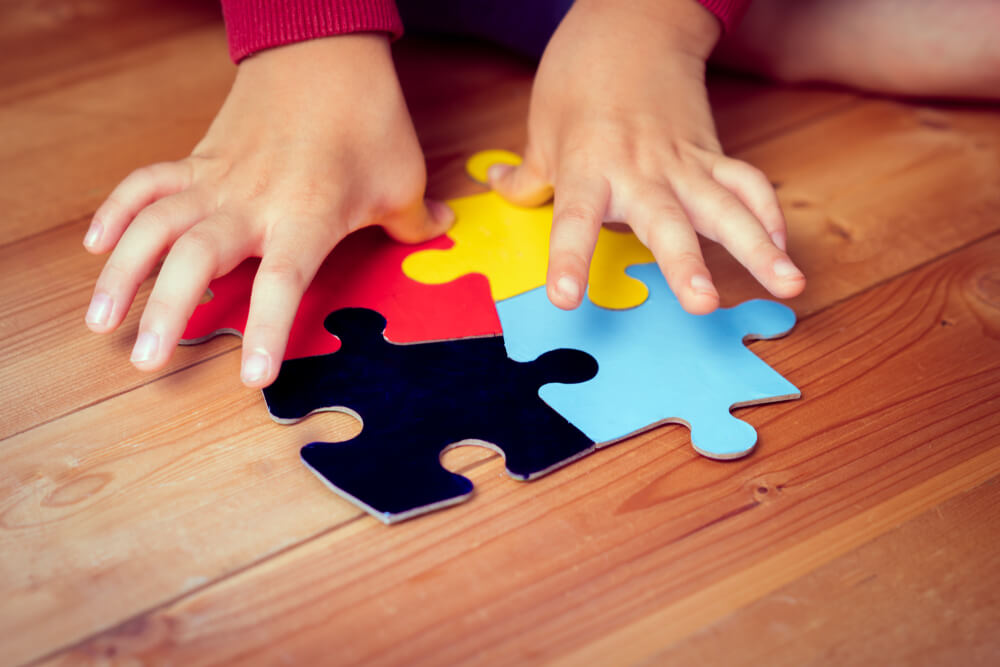 An Autistic Child's Hands Playing a Puzzle Symbol of Public Awareness for Autism