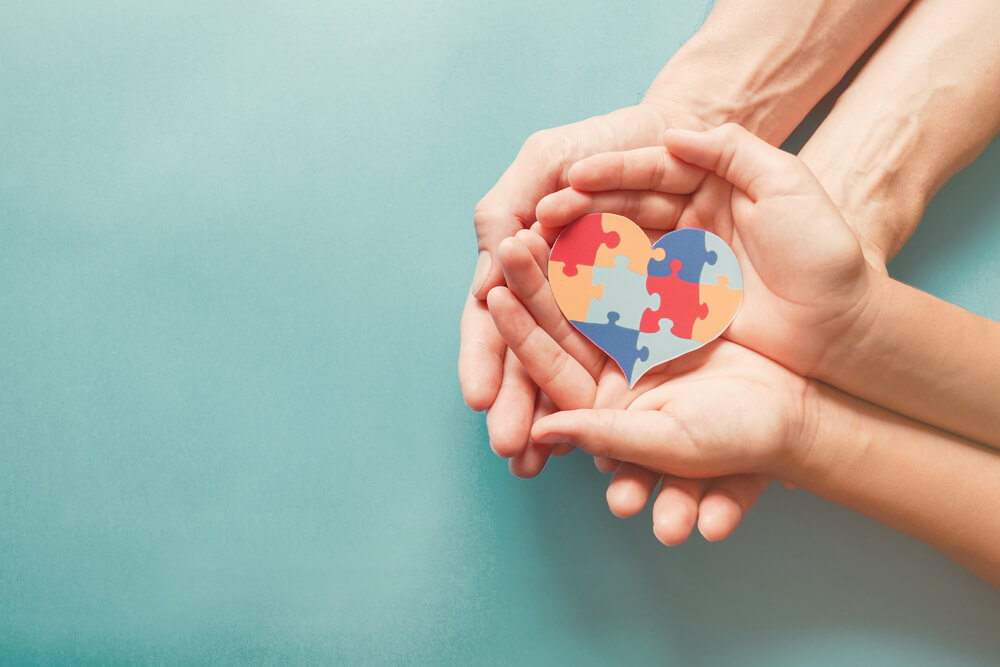 Adult and Child Hands Holding Jigsaw Puzzle Heart Shape