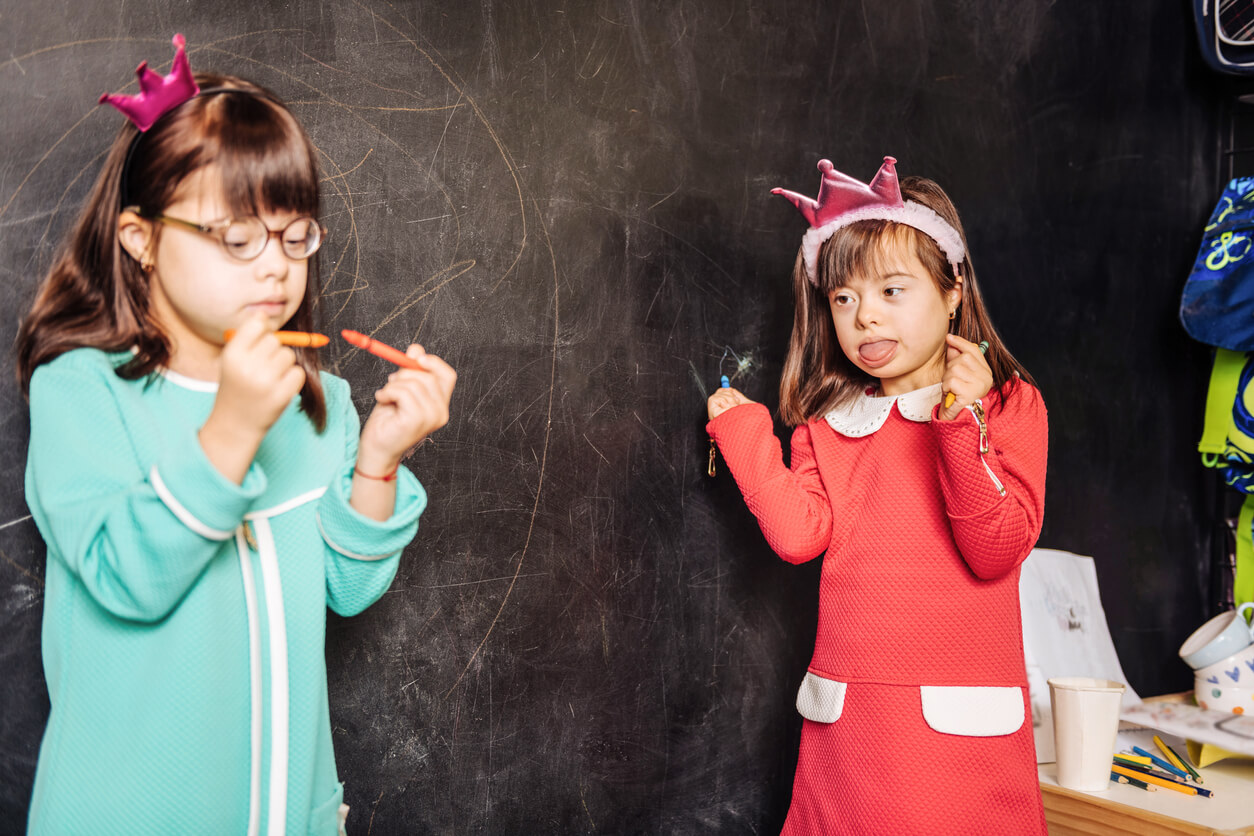 Two Funny Beautiful Sisters With Genetic Disorders Having Fun Near the Blackboard