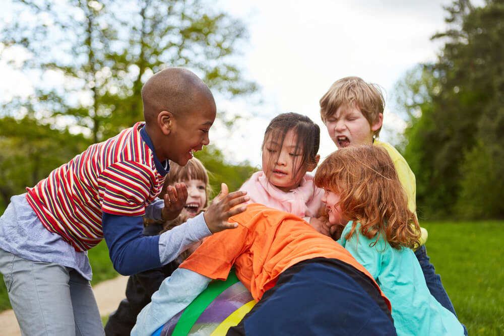 Multicultural Children Have Fun in the Park in the Summer When Competing For a Ball