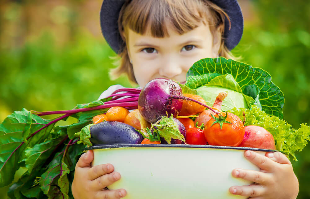 Kid Holding a Bowl Full of Fruits and Vegetables