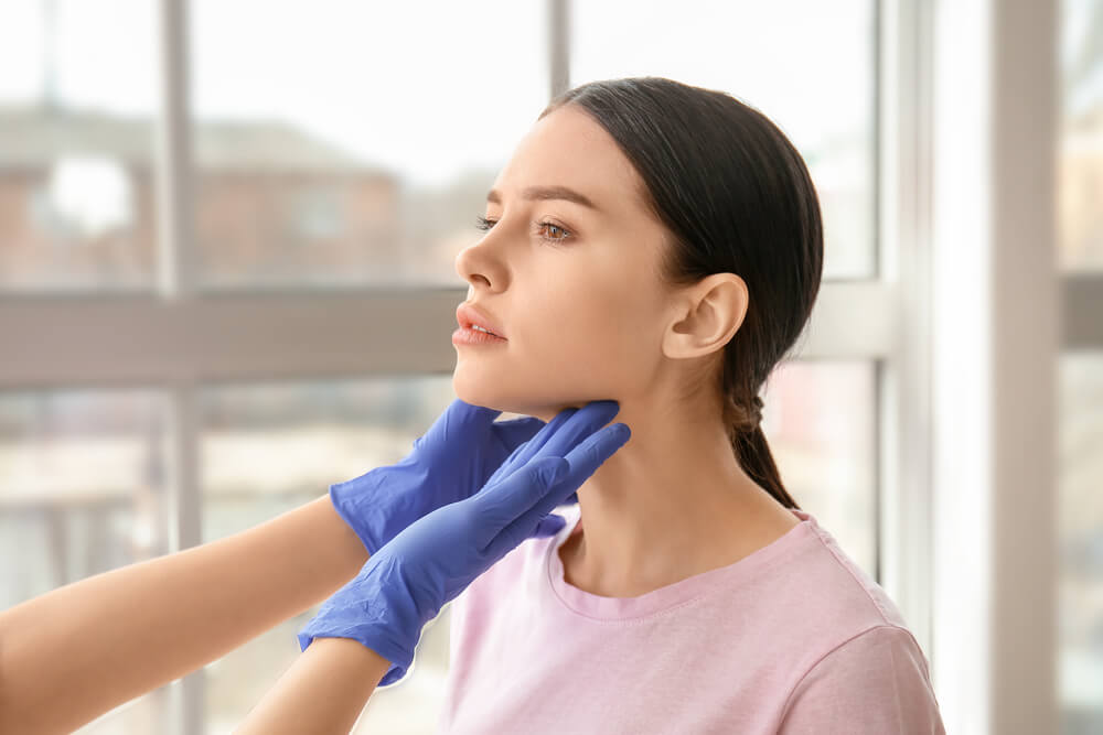 Endocrinologist Examining Thyroid Gland of Young Woman in Clinic