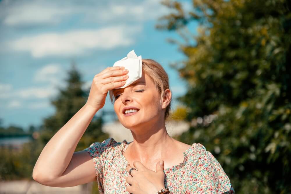 Portrait of Blonde Pretty Woman Having Hot Flash and Sweating on Sun Heat at Summer Day Outdoors