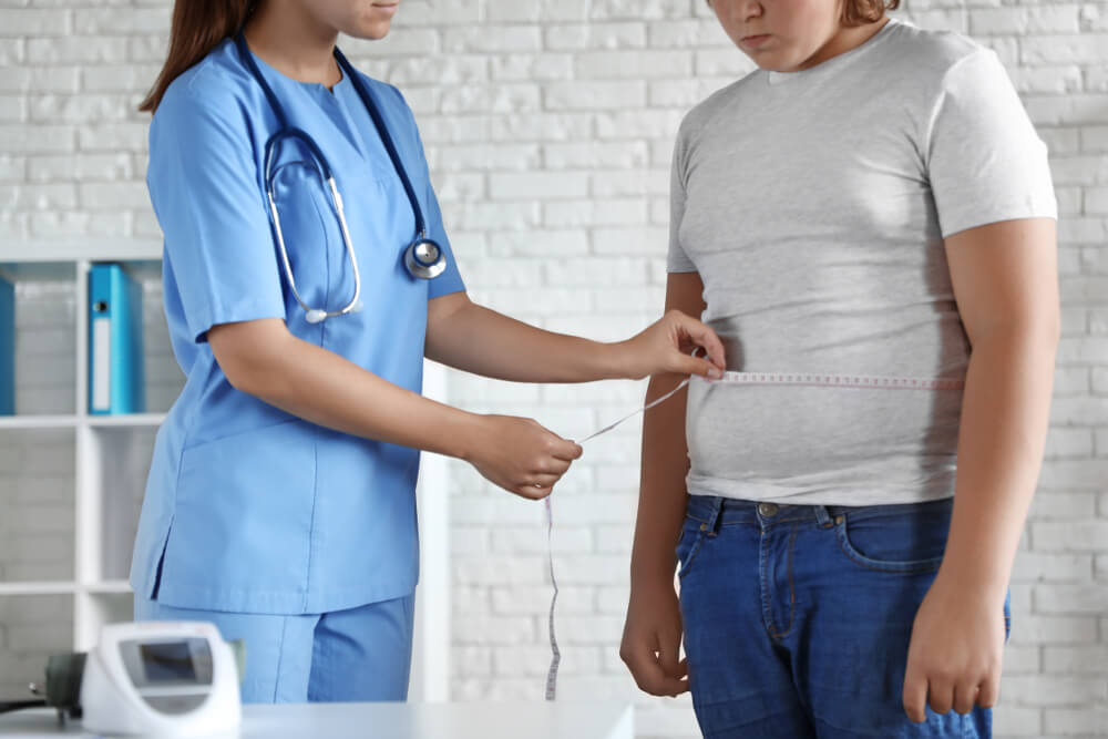 Female Doctor Measuring Overweight Boy in Clinic, Closeup View