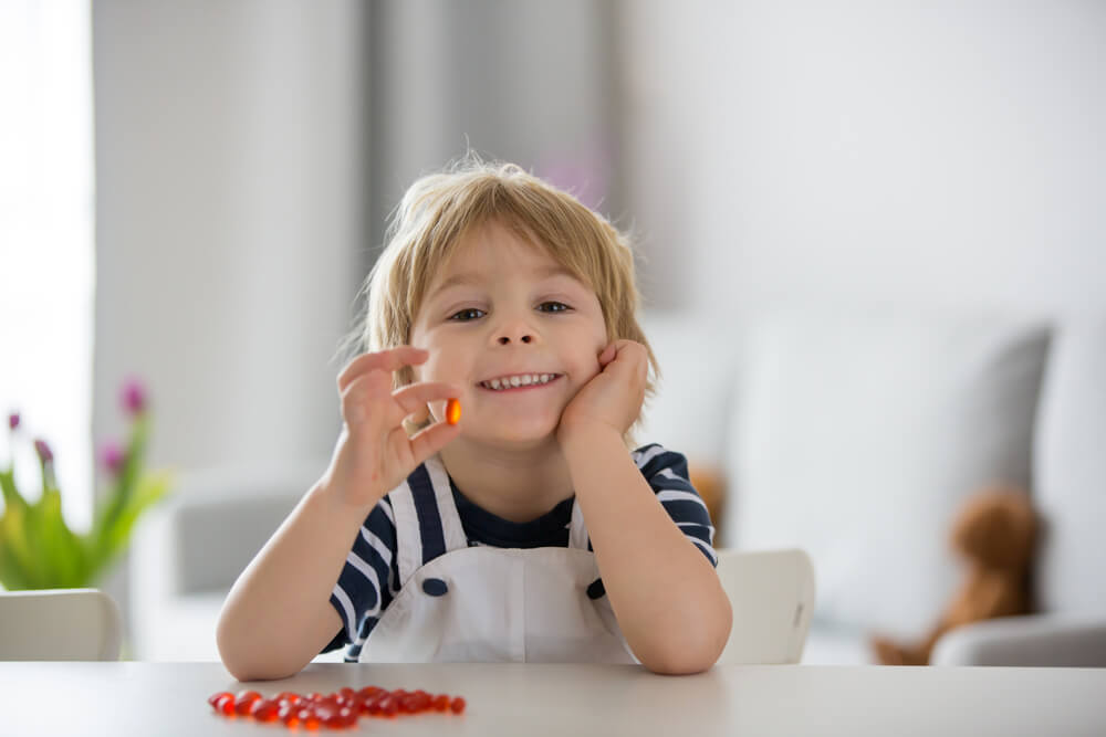 Toddler Boy, Eating Alfa Omega 3 Child Supplement Vitamin Pills at Home for Better Immunity