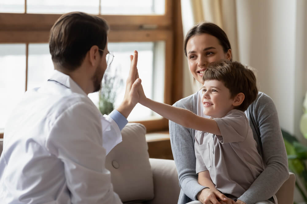 Happy Little Boy Patient With Mom Give High Five to Caring Male Pediatrician After Consultation in Hospital