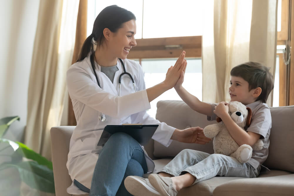 Smiling Young Female Doctor Give High Five to Little Boy Patient at Consultation in Clinic