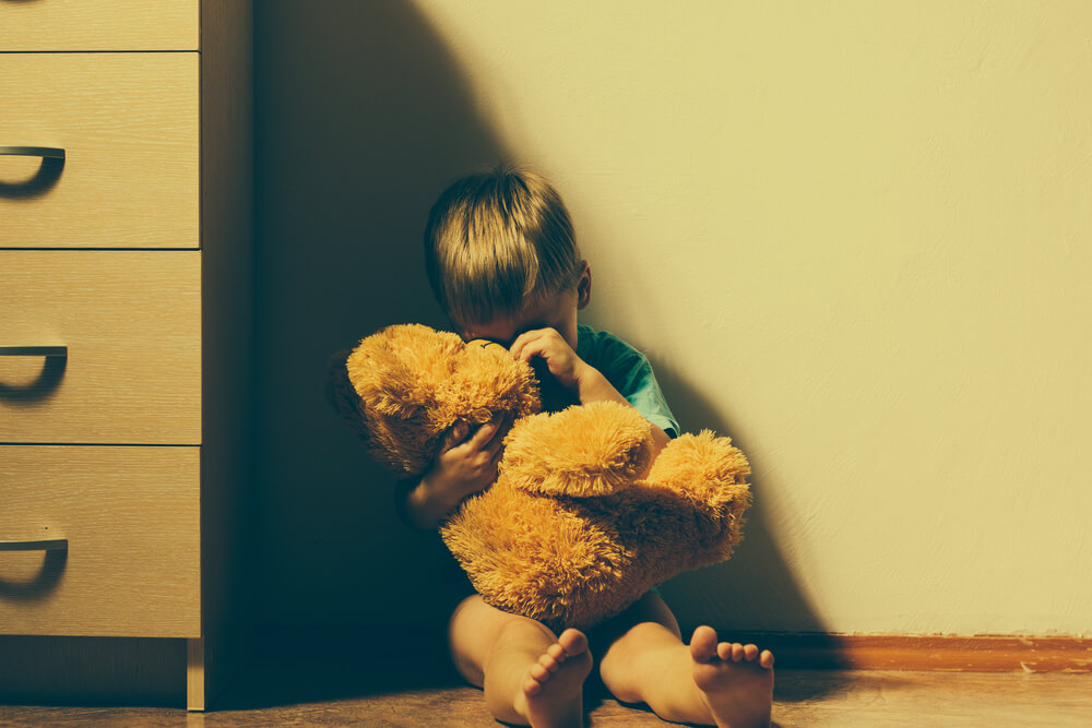 Lonely Scared Boy Sitting in Corner, Hugging His Teddy Bear and Crying