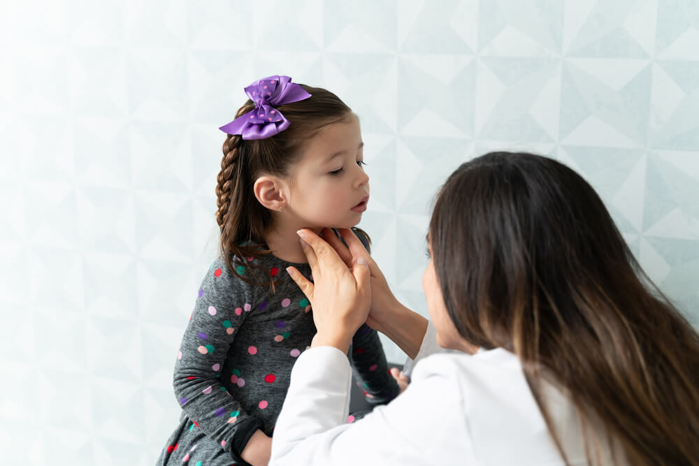 Female Pediatrician Examining Thyroid Gland of Little Girl During Medical Checkup