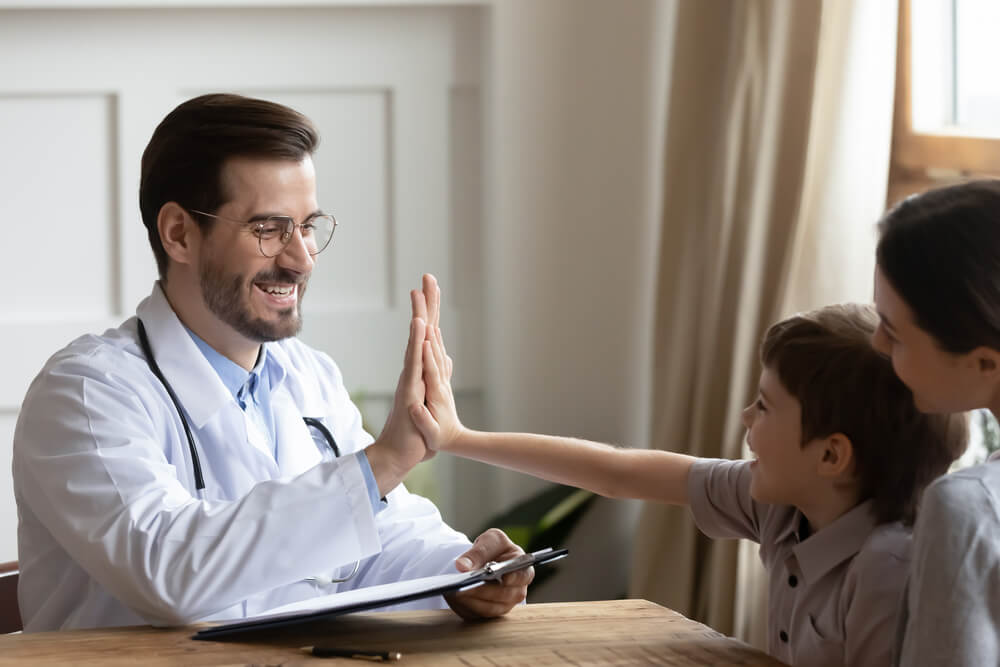 Doctor Give High Five To Cute Small 7S Boy Patient at Consultation With Mom in Hospital